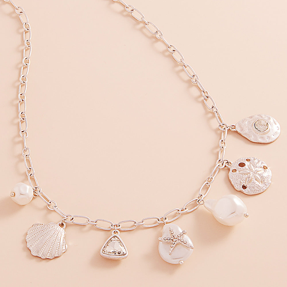 Coastal charm necklace with metal seashell and sand dollar charms, starfish accents and pearls in a station design