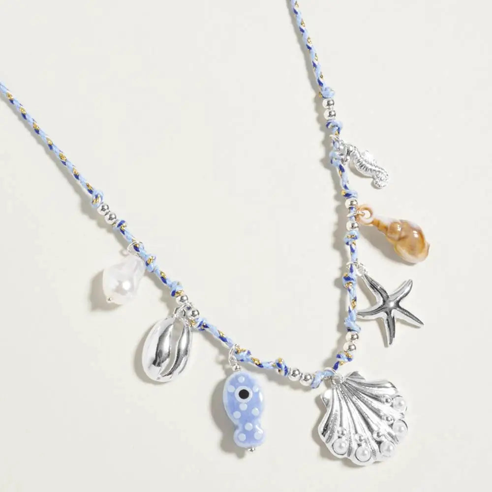 Pearl seashell starfish seahorse charm necklace with twisted fabric chain styled as a coastal statement accessory.