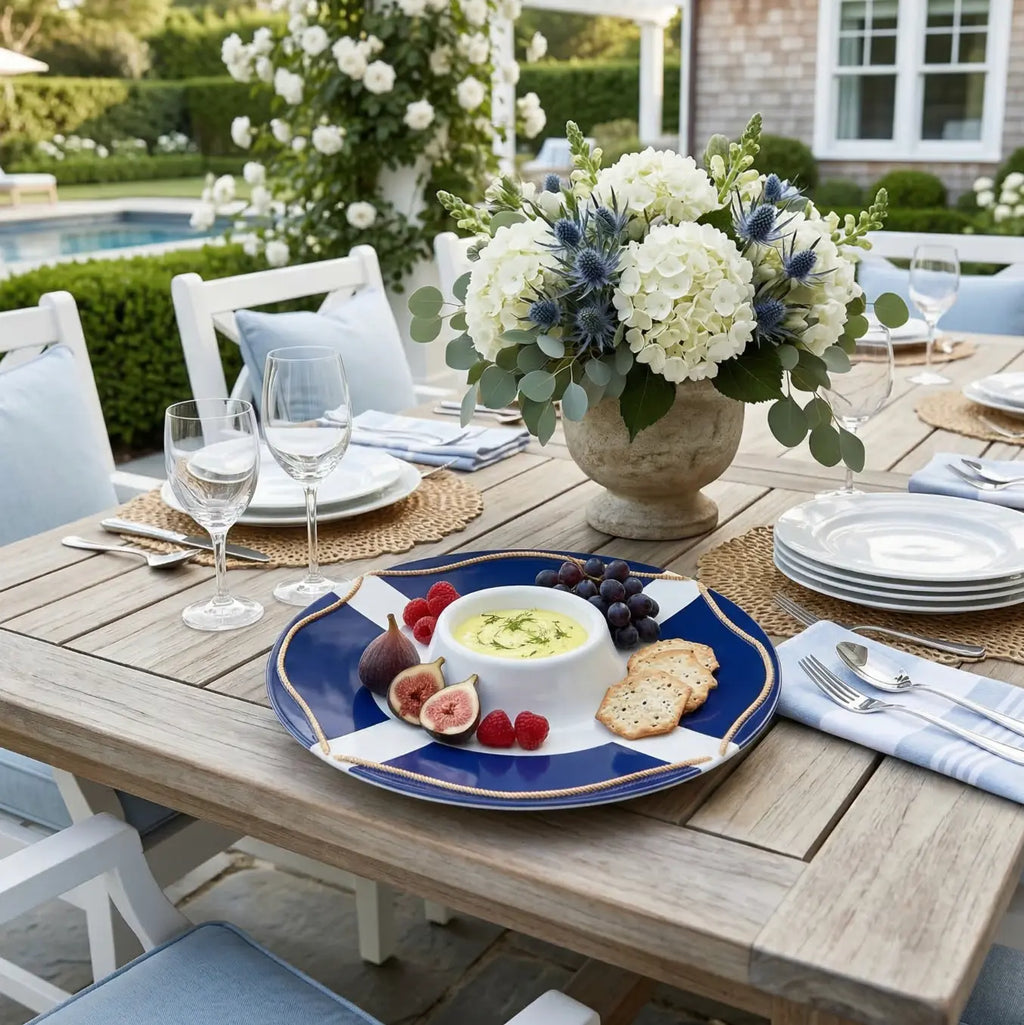 Life Saver Serving Platter with built-in bowl in the middle, on a rustic outdoor table with fruit, crackers and flowers.