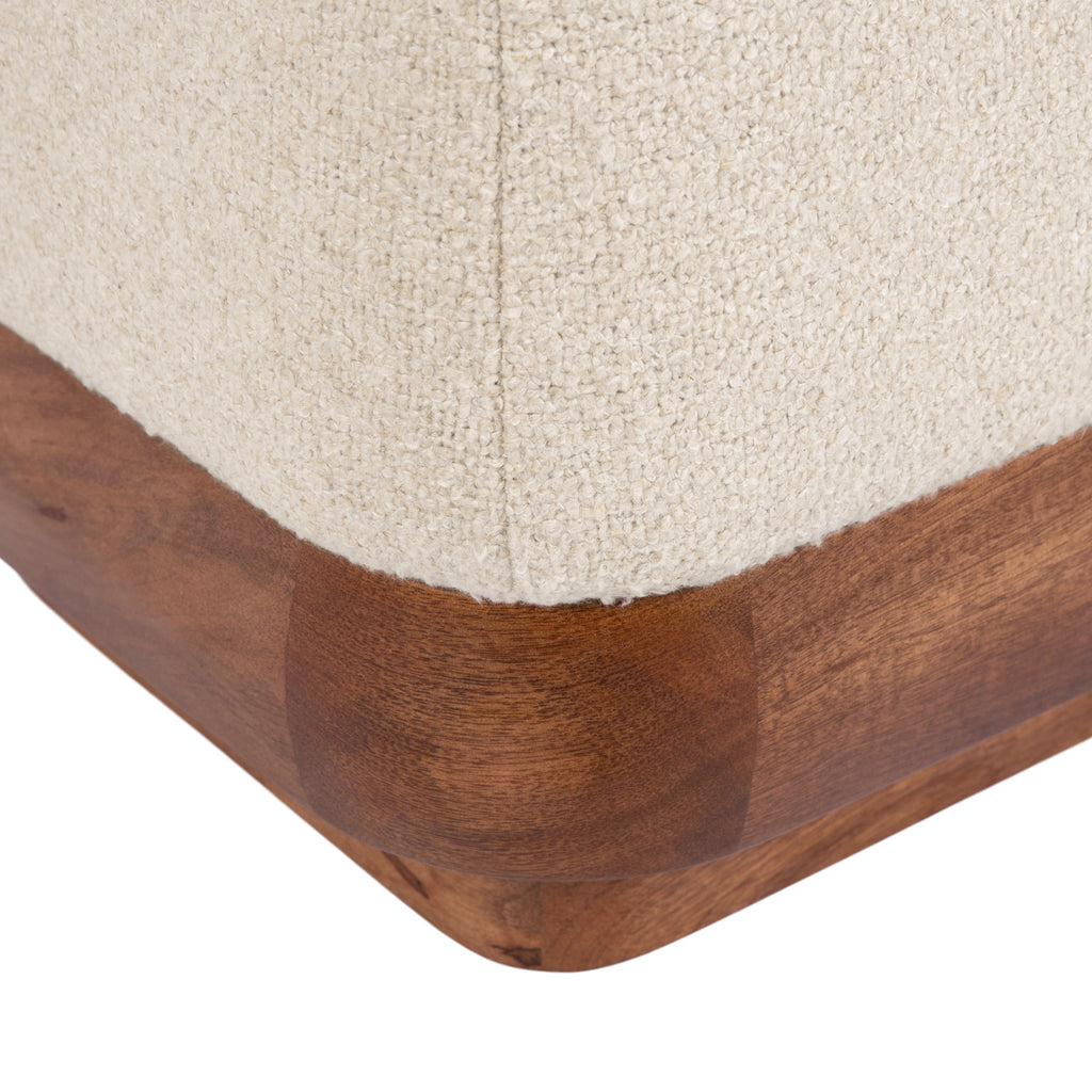 Off-white boucle ottoman styled as a living room accent footstool