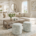 Pair of round upholstered poufs with a pale aqua and ivory floral pattern in a bright coastal living room.