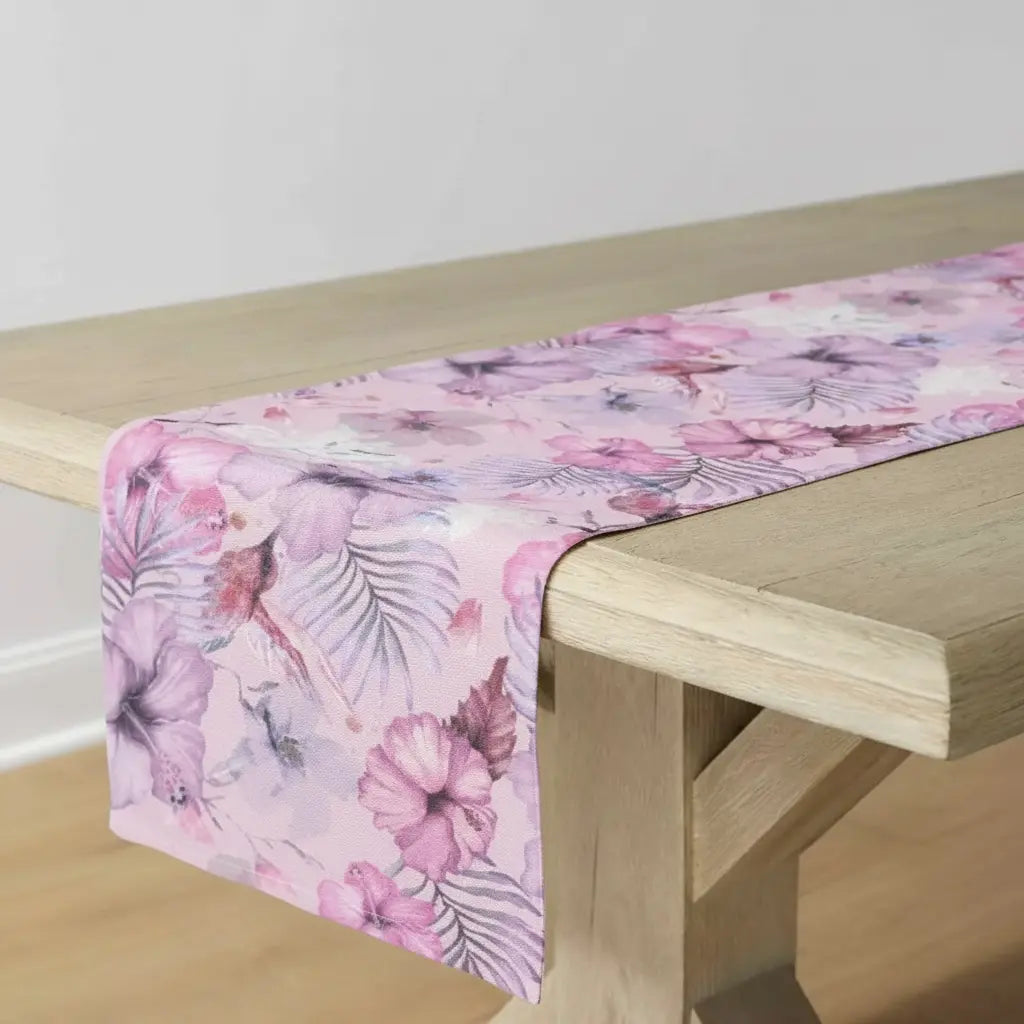 Pink tropical floral table runner with palm-inspired pattern on a light wood table
