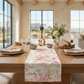 Pink floral table runner on a light wood dining table with soft spring decor.