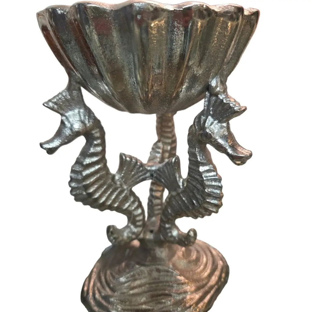Three sculpted seahorses wrap around a pedestal, supporting a coastal serving bowl in polished aluminum.