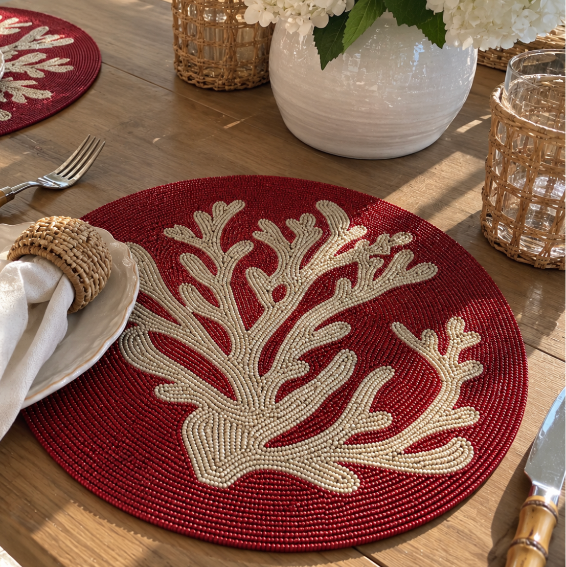 Red coral beaded placemat styled on an elegant coastal dining table.