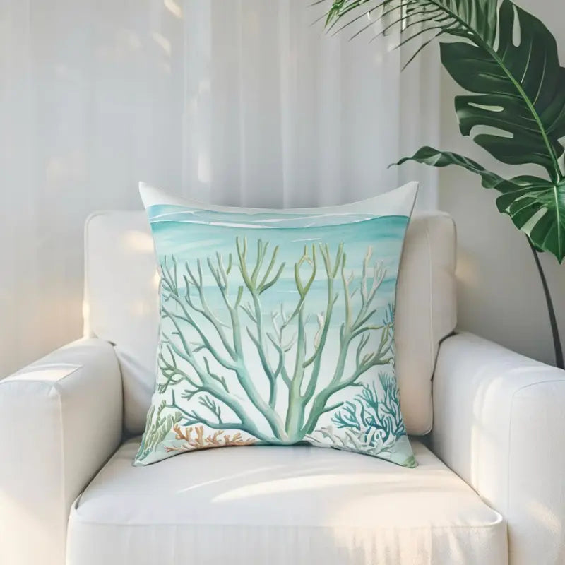 Coastal Reef Throw Pillow with turquoise coral reef illustration on a white armchair.