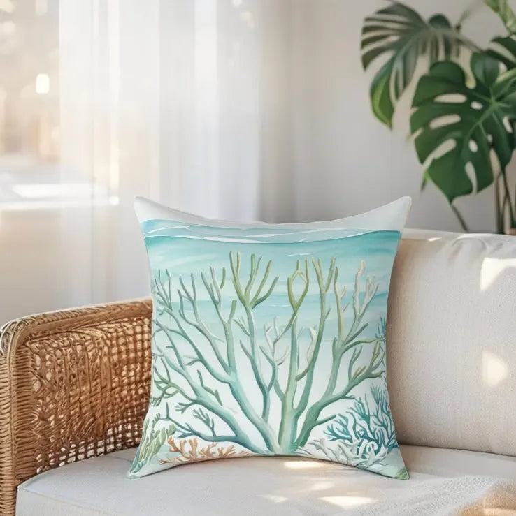 Coastal Reef Throw Pillow with turquoise coral reef motif on a light sofa in a sunlit living room.