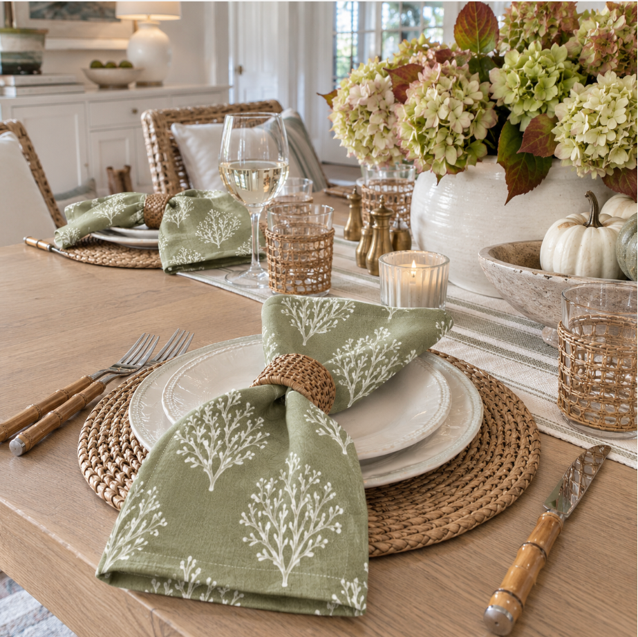 Green and white patterned linen napkins on a rustic wood table with white pumpkins and autumn florals for Thanksgiving