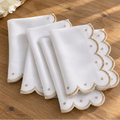 Scalloped edge embroidered napkins with elegant decorative detailing.