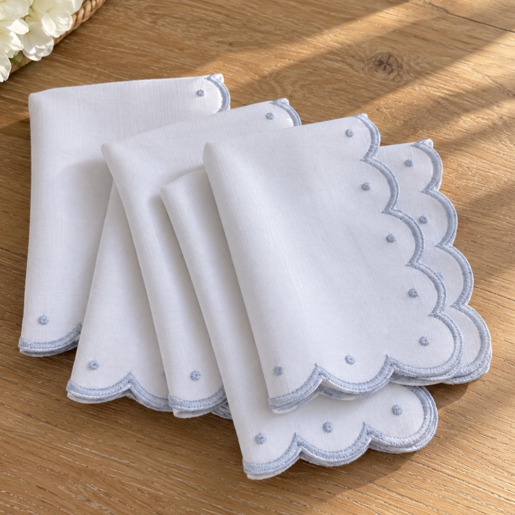Scalloped embroidered dinner napkins styled on a dining table.