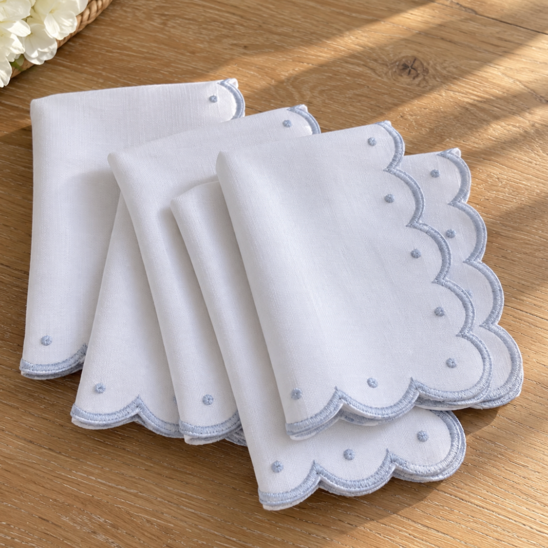 Scalloped embroidered dinner napkins styled on a dining table.