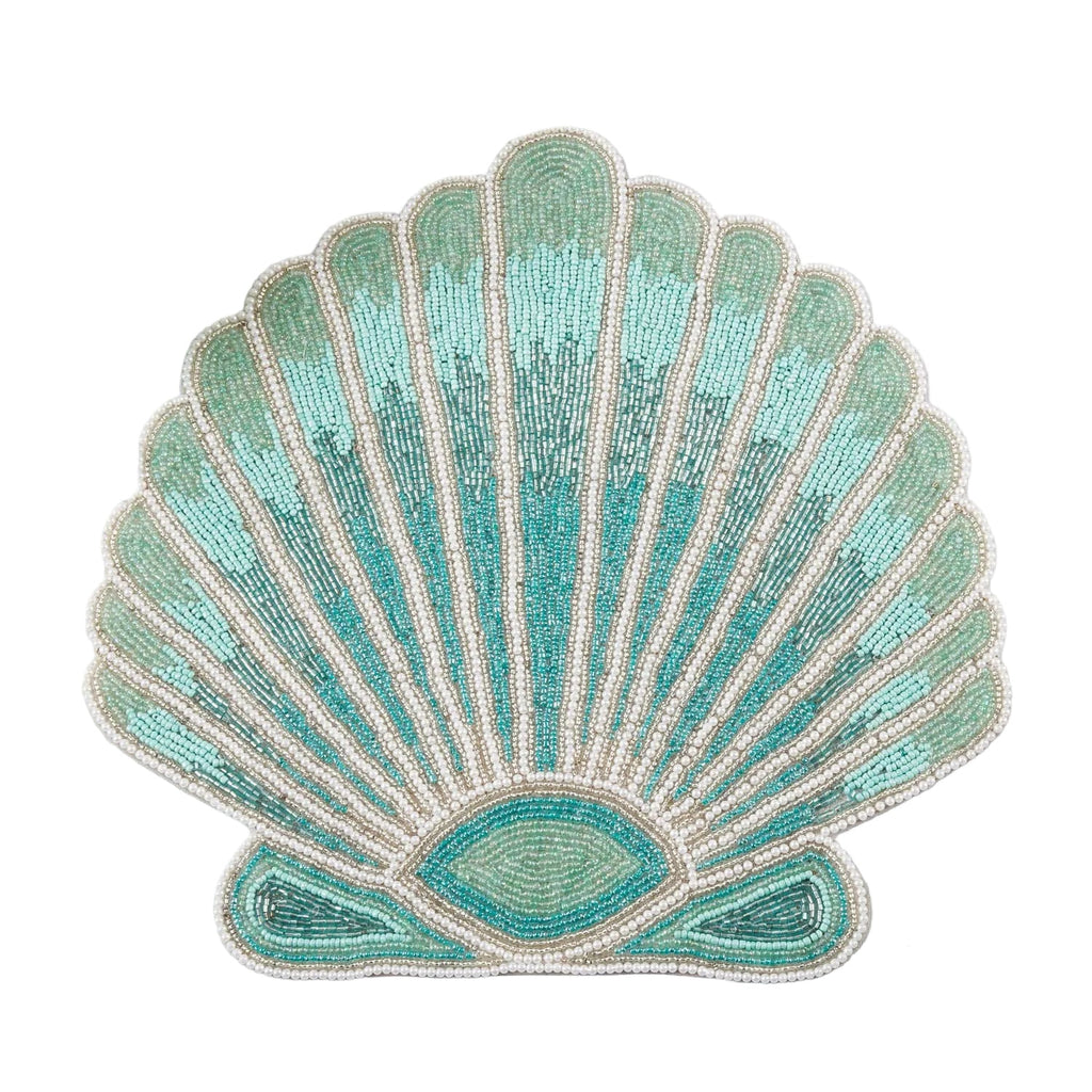 Shell‑shaped beaded placemat in soft aqua and white beads styled with clear glassware and neutral napkins.