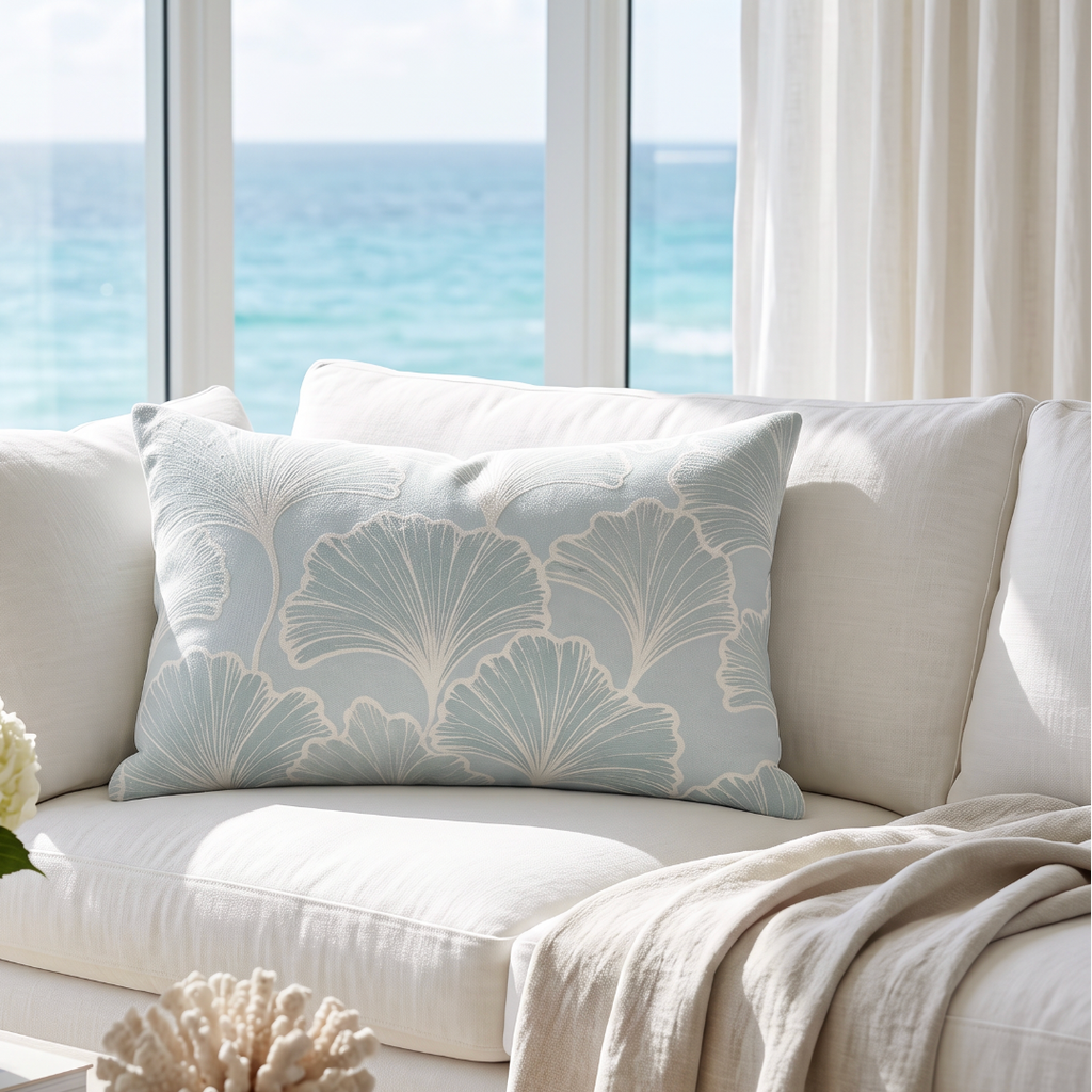 Seafoam coastal lumbar throw pillow with a white leaf design layered on a light linen sofa for neutral beach house decor
