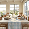 Seafoam green gingham check table runner on a light wood farmhouse dining table.