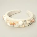 Beachy seashell and pearl stone embellished statement headband photographed in a flatlay with shells