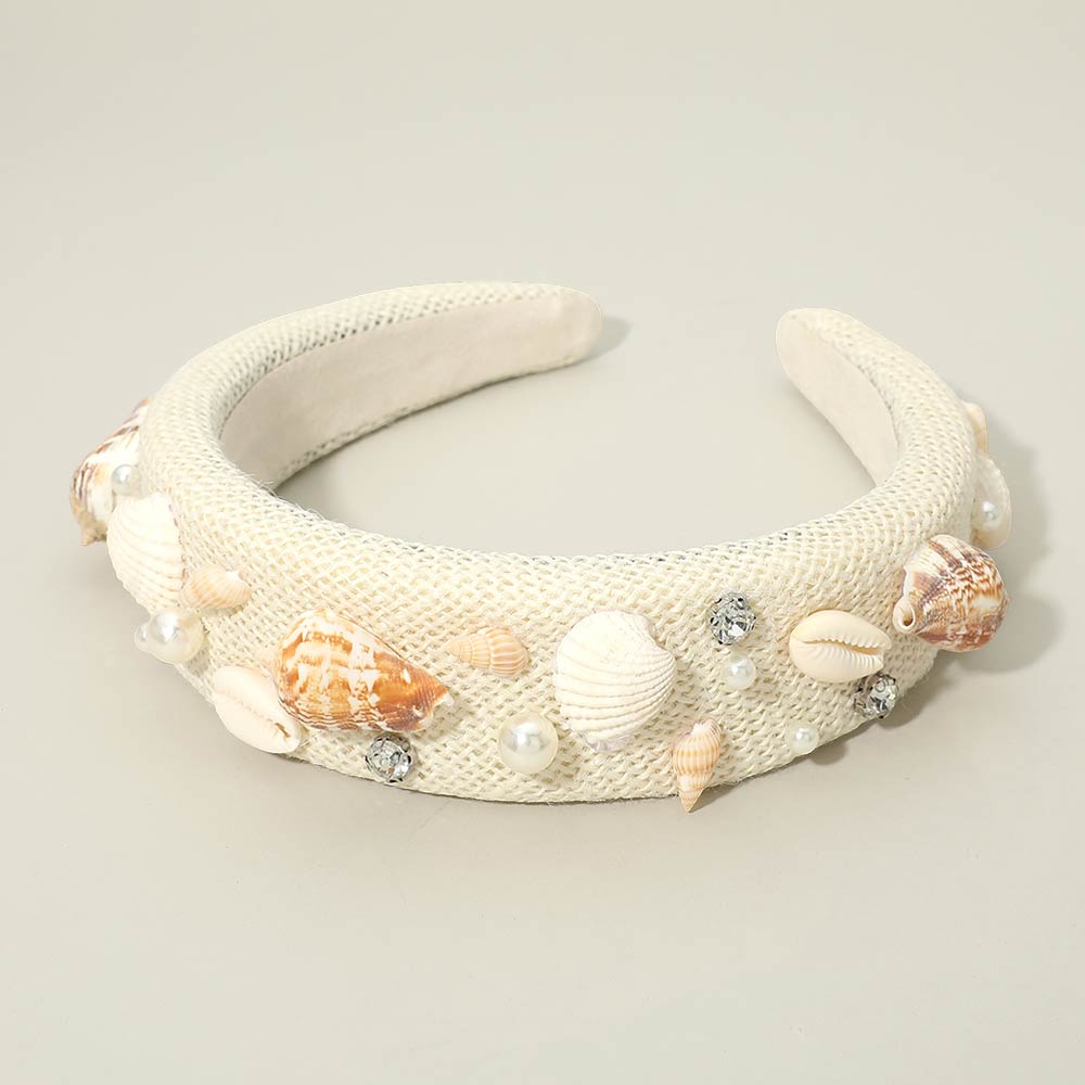 Beachy seashell and pearl stone embellished statement headband photographed in a flatlay with shells
