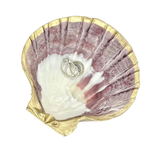Decorative seashell trinket dish holding rings and jewelry on a bedroom nightstand