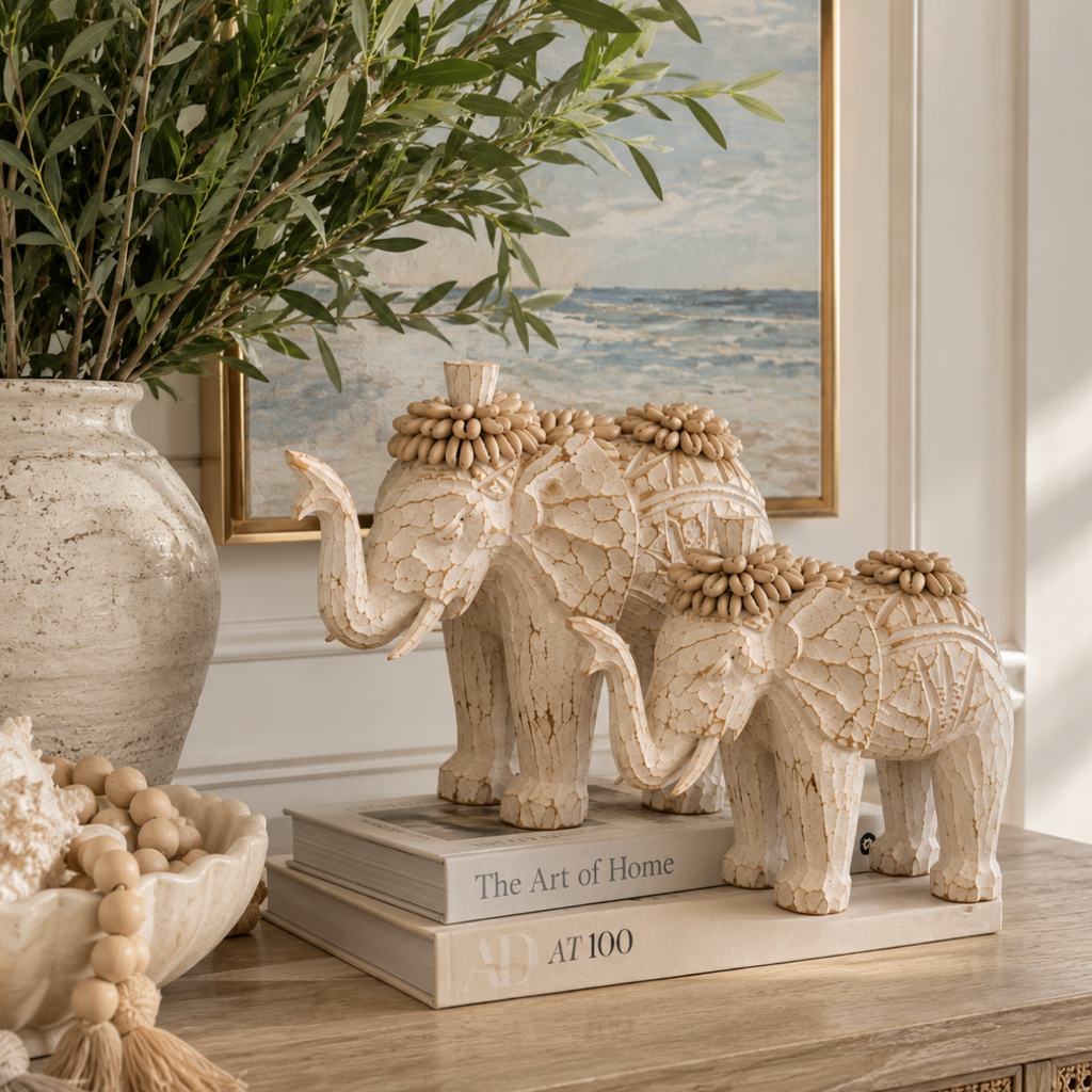 Pair of cream shell elephant figurines styled on a natural wood console in a luxury coastal-inspired home.