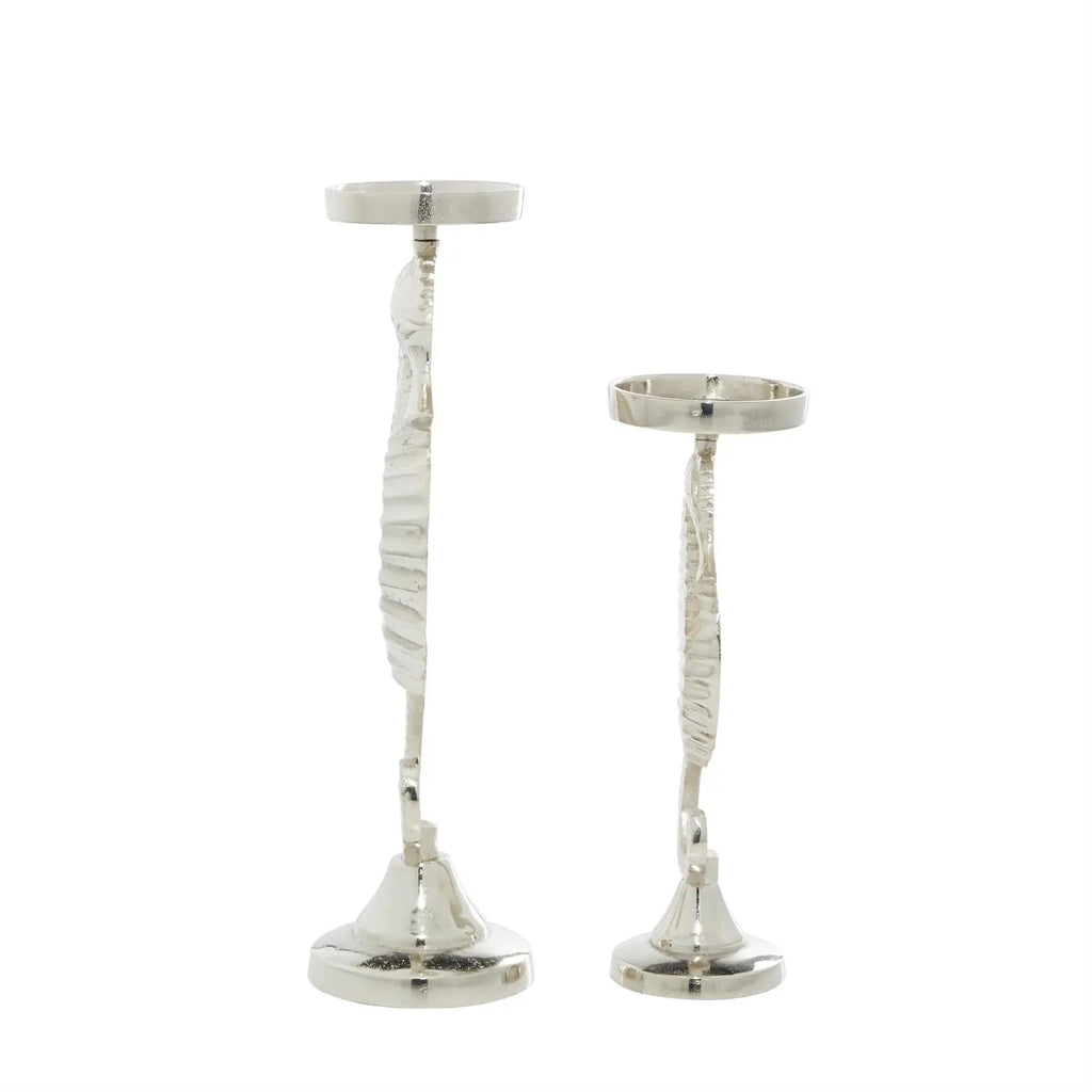 Pair of silver seahorse candle holders on sculpted aluminum pedestals, polished finish reflects candlelight.