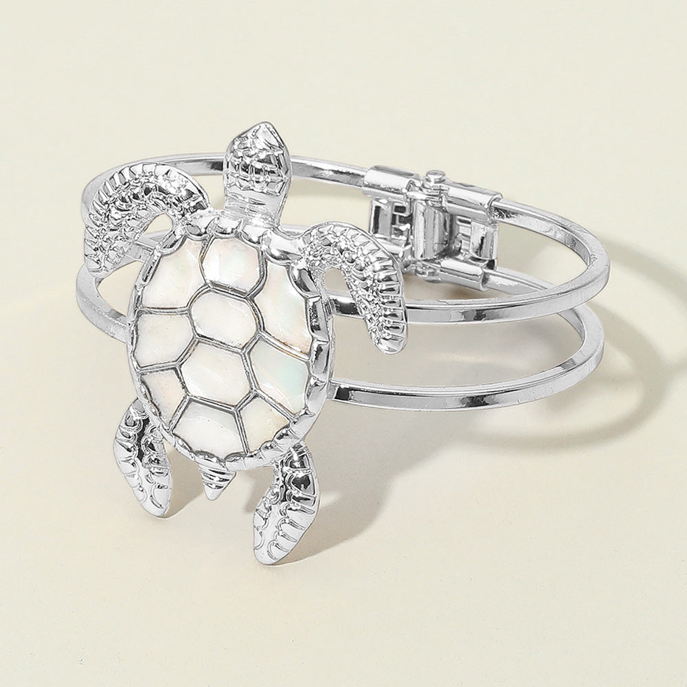 Silver turtle bracelet with mother of pearl shell centerpiece shown as coastal statement jewelry.