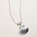Delicate silver seashell charm necklace shown as beach inspired everyday jewelry