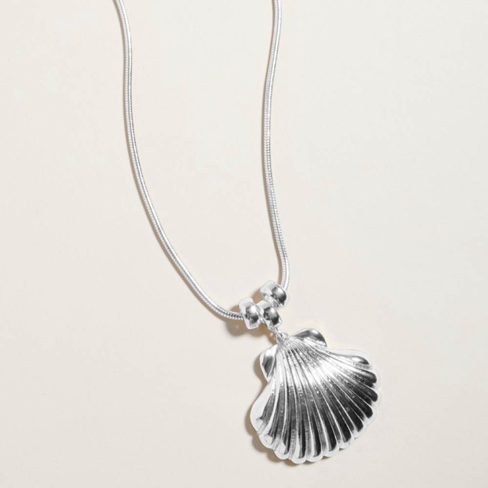 Delicate silver seashell charm necklace shown as beach inspired everyday jewelry