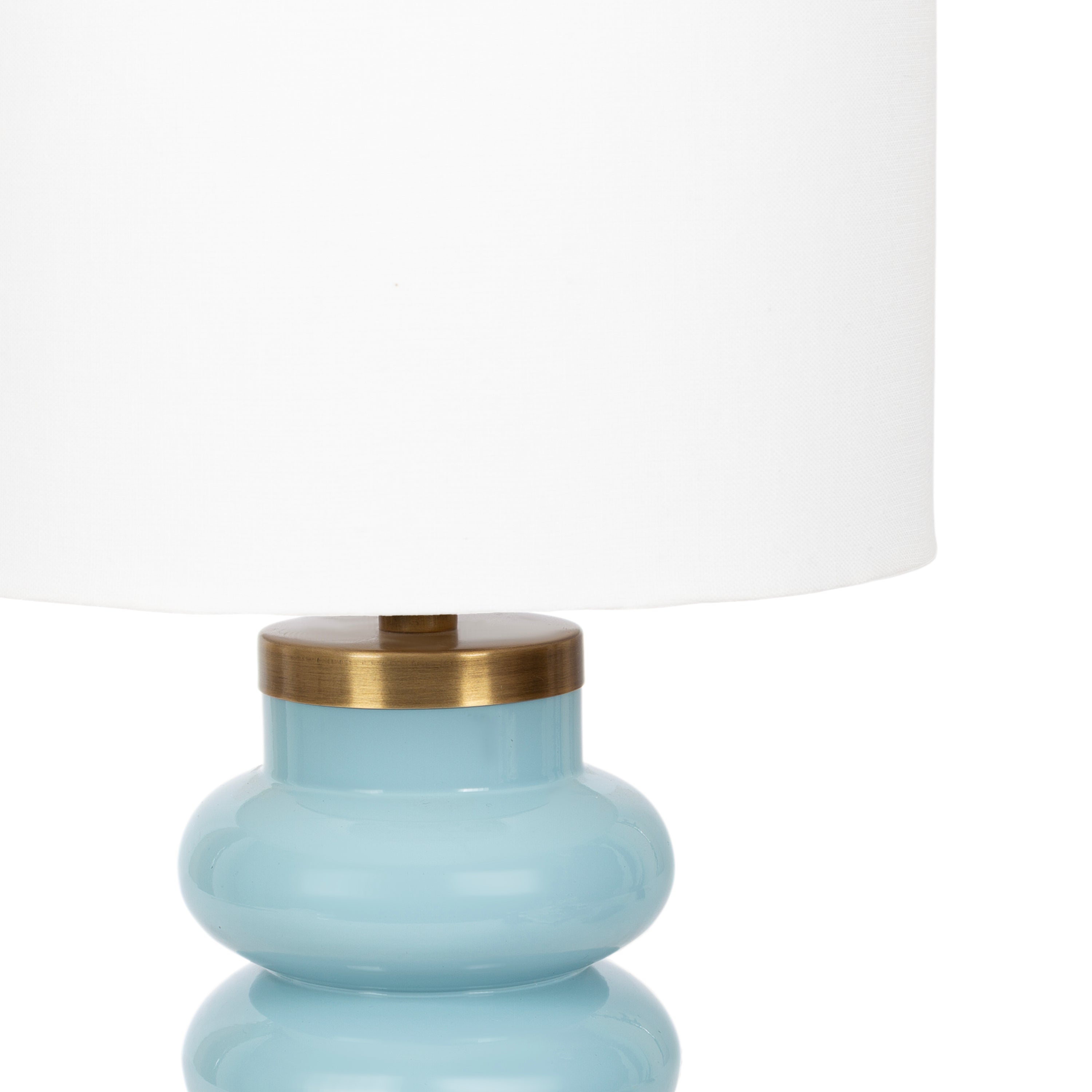 Glossy soft blue table lamp adding sculptural color and warm light to a neutral coastal interior.