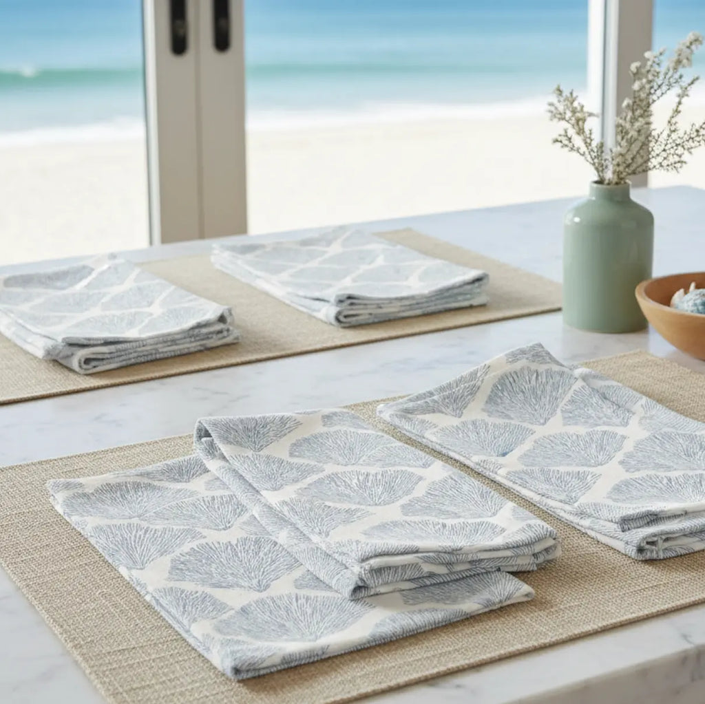Bar Harbor Coral Linen Napkins set of 4 with blue seashell pattern on a coastal table.