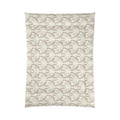 Tan pattern comforter on a bed in a light, airy beach house bedroom
