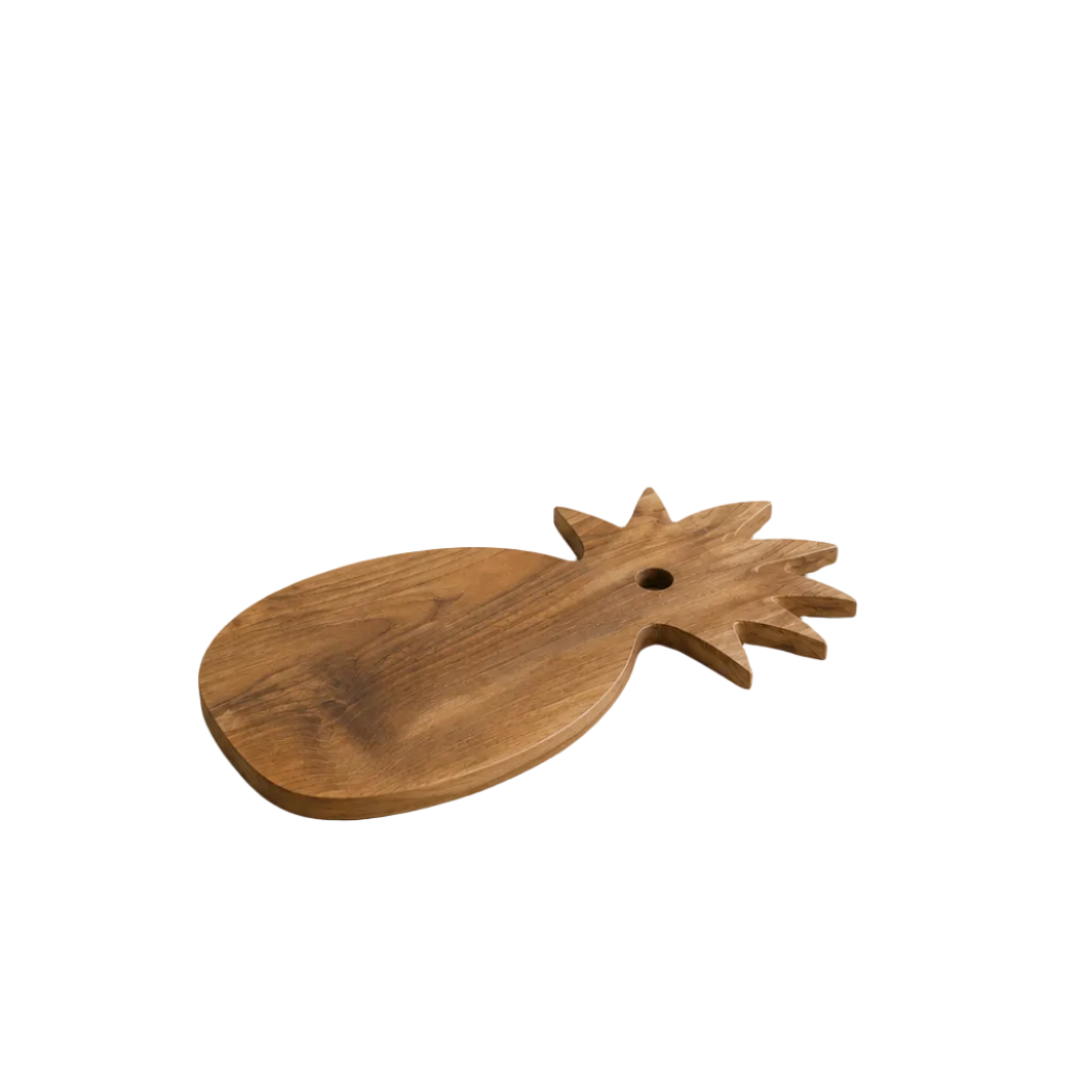 Close-up of the natural wood grain and handcrafted pineapple shape of a solid teak cutting board.