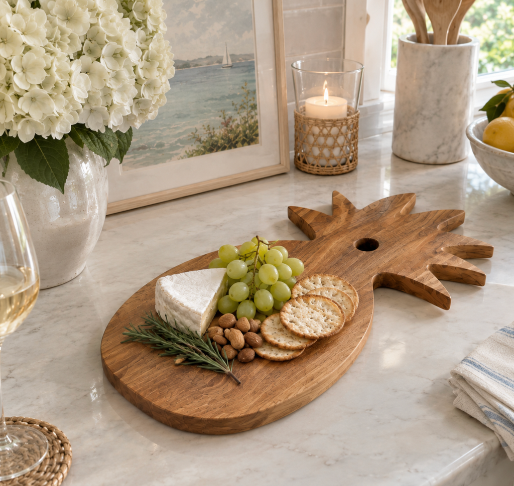 Natural teak pineapple cheese board used to serve appetizers and fresh fruit during a casual gathering.