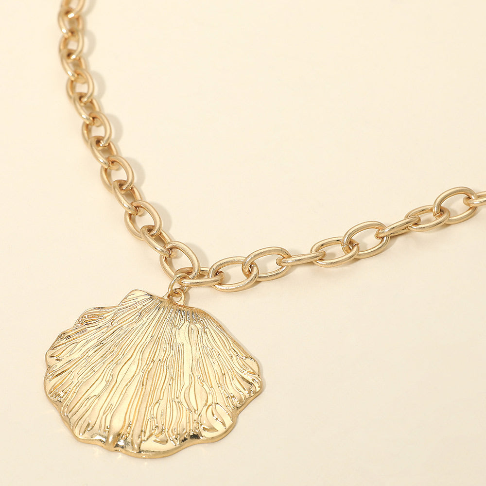 Coastal textured seashell pendant necklace on a metal chain shown as beach inspired everyday jewelry.