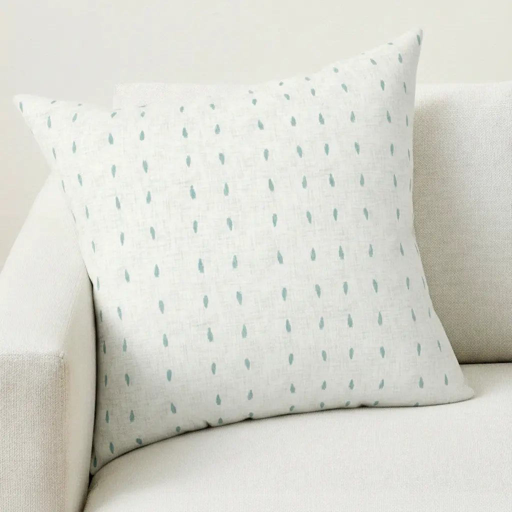 Capri Polka Dot Throw Pillow with turquoise dots on white linen, resting on a light sofa.