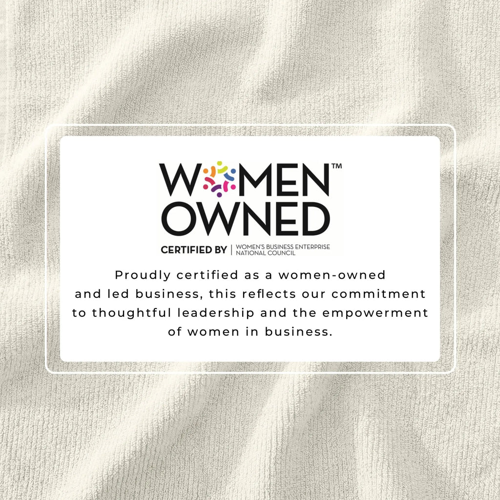 Bath towel set texture with a Women-Owned certification badge on beige Turkish cotton fabric